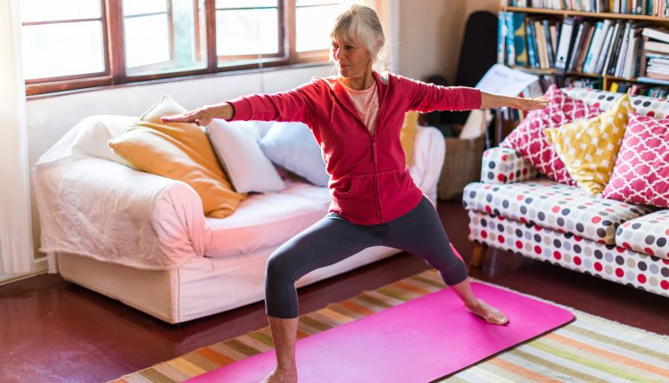 Oudere dame doet aan yoga in kleurrijke yoga kamer