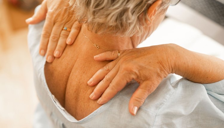 Vrouw masseert haar pijnlijke schouderbladen