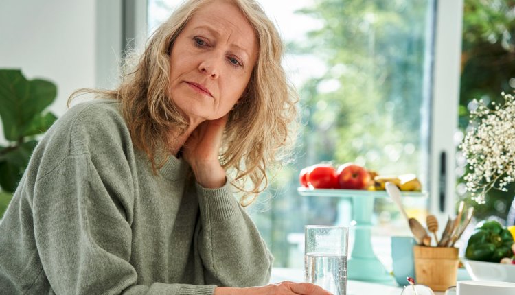 Vrouw kijkt zorgelijk, heeft klachten aan schouders en armen