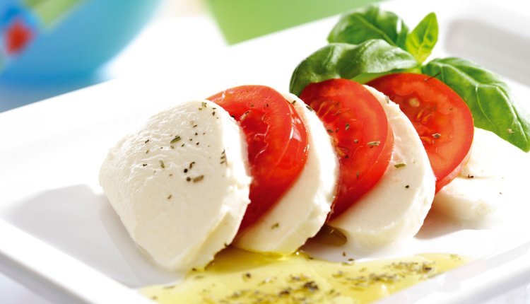 Caprese op een bord, oftewel mozzarella, tomaat en basilicum met olijfolie