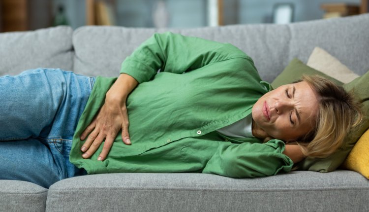 Buikgriep norovirus vrouw op de bank met buikpijn