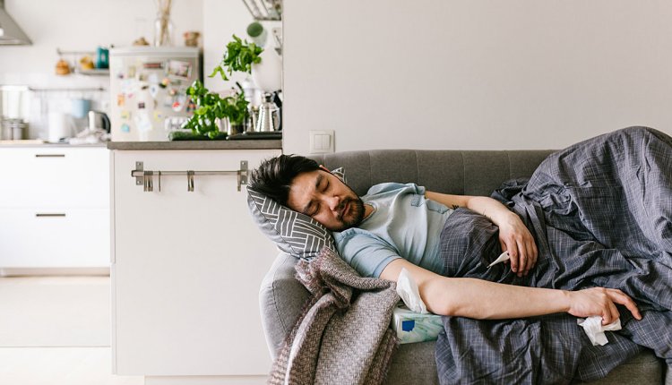 Man ligt op bank in woonkamer met griep