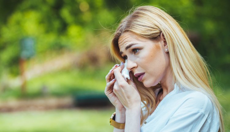 Vrouw met zakdoek dept haar tranende ogen