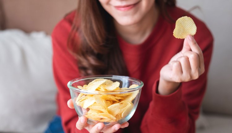 Vrouw eet chips uit een kommetje