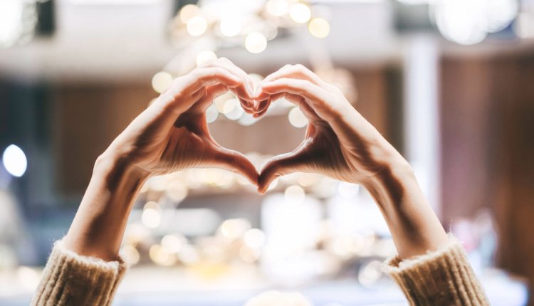 Vrouw maakt met haar handen de vorm van een hart in kerstsfeer