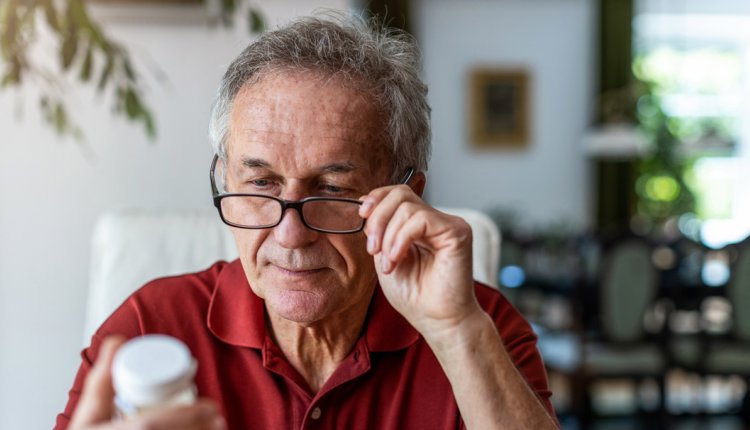 Man leest bijsluiter op zijn medicatie