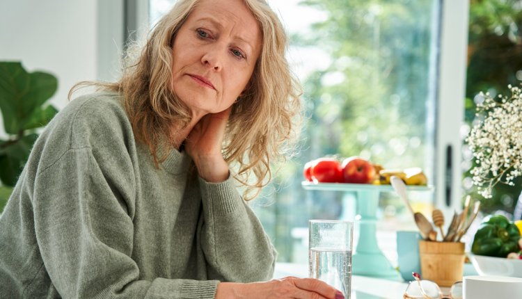 Vrouw drinkt glas water kijkt zorgelijk