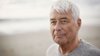 Man op het strand in zijn trui op een mooie herfstdag