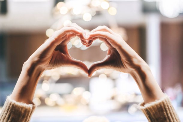 Vrouw maakt met haar handen de vorm van een hart in kerstsfeer