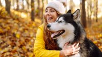 Vrouw in de herfst met husky in het bos