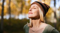 Vrouw staat in het bos in de herfstzon