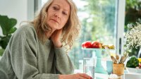 Vrouw drinkt glas water kijkt zorgelijk