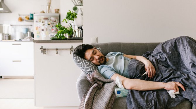 Man ligt op bank in woonkamer met griep