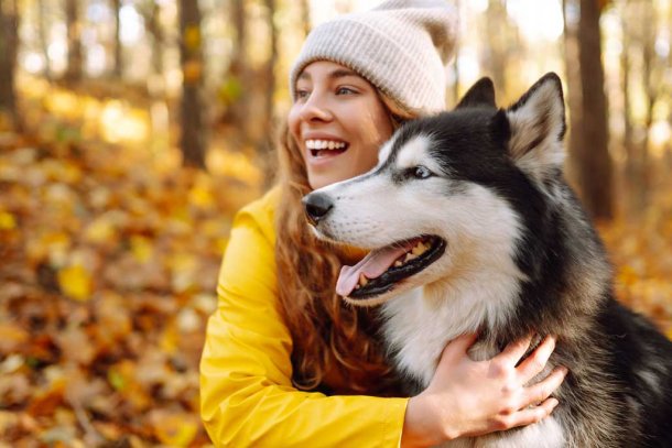 Vrouw in de herfst met husky in het bos