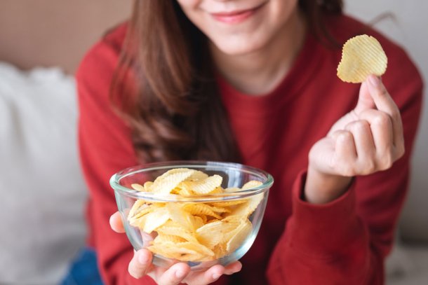 Vrouw eet chips uit een kommetje