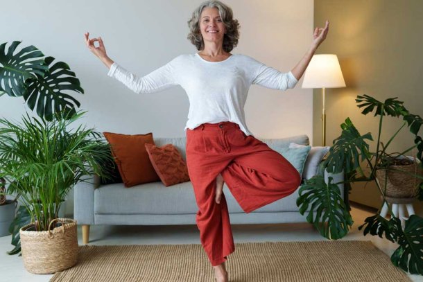 Vrouw balanceert op een been in de woonkamer